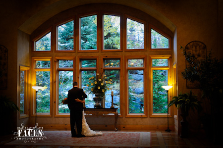 Bride and groom hugging in front of window with beautiful scenery