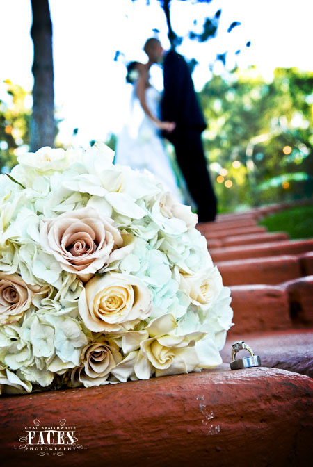 Bouquet and rings with groom and bride kissing in the background