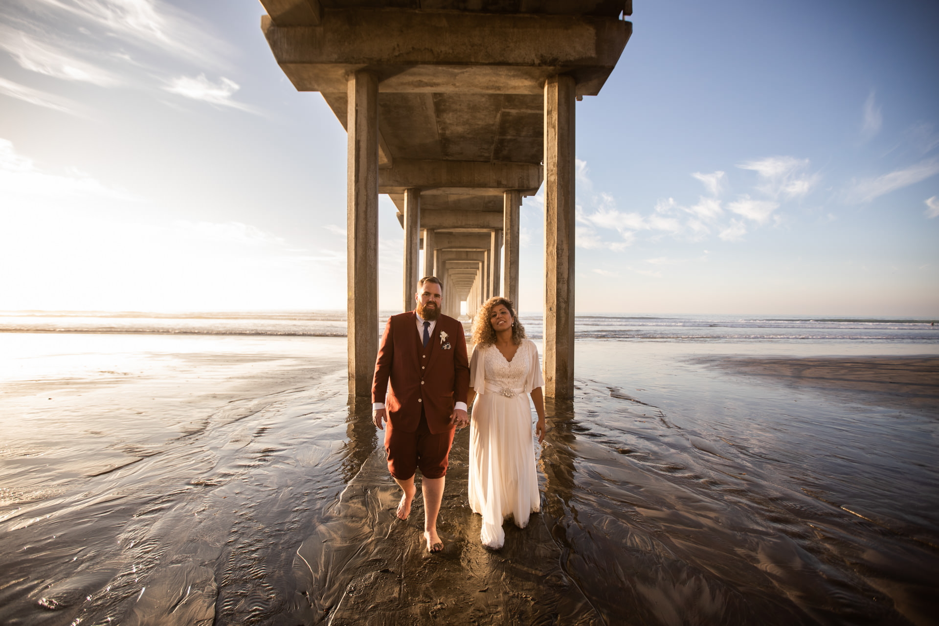 Gerusa and Eric Walking Under Scripps Pier Beach Wedding