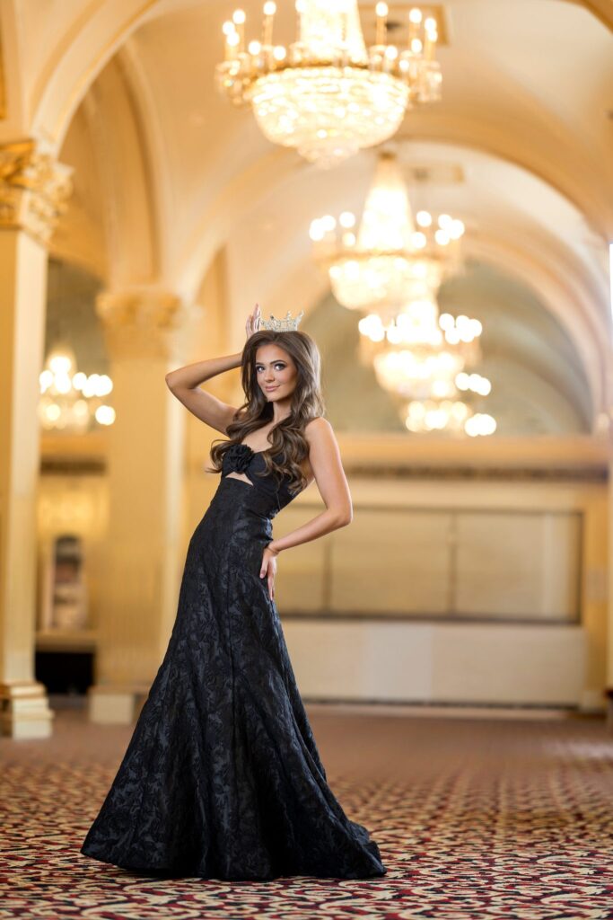 Elle Anderson, Miss Utah's Teen 2026, in a black gown and crown in a chandelier ballroom
