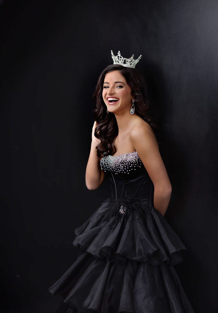 Candid: titleholder mid-laugh in a black gown and crown
