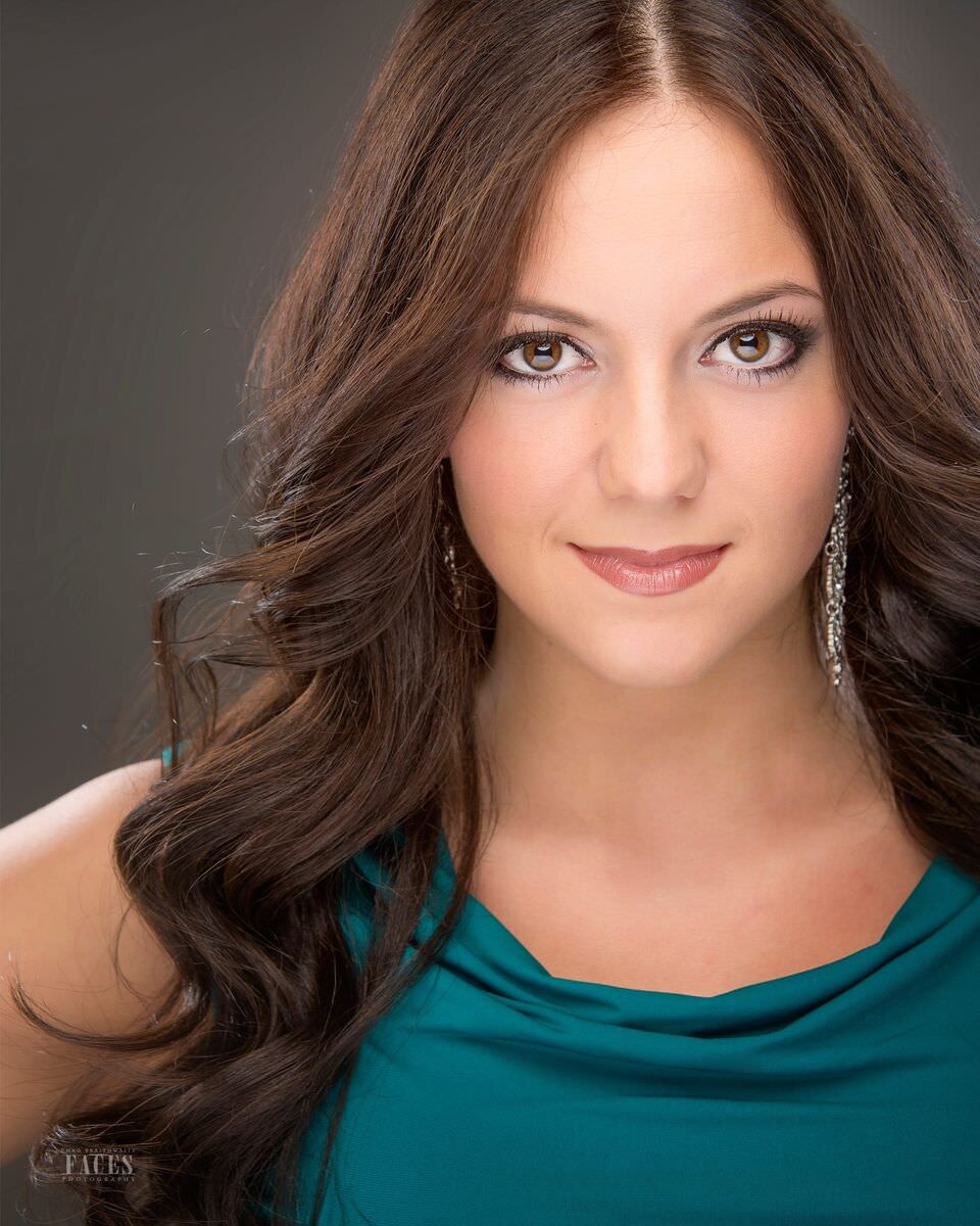 Headshot: auburn hair, emerald neckline, soft smile