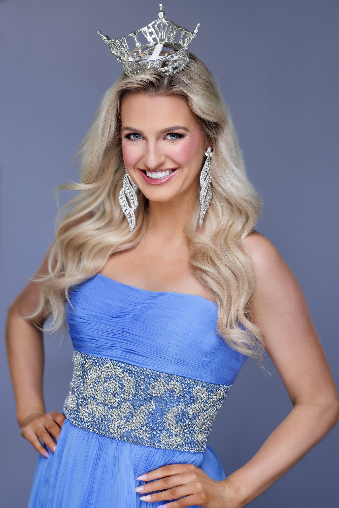 Miss Utah headshot: crown, blue gown, big smile on a soft blue studio backdrop