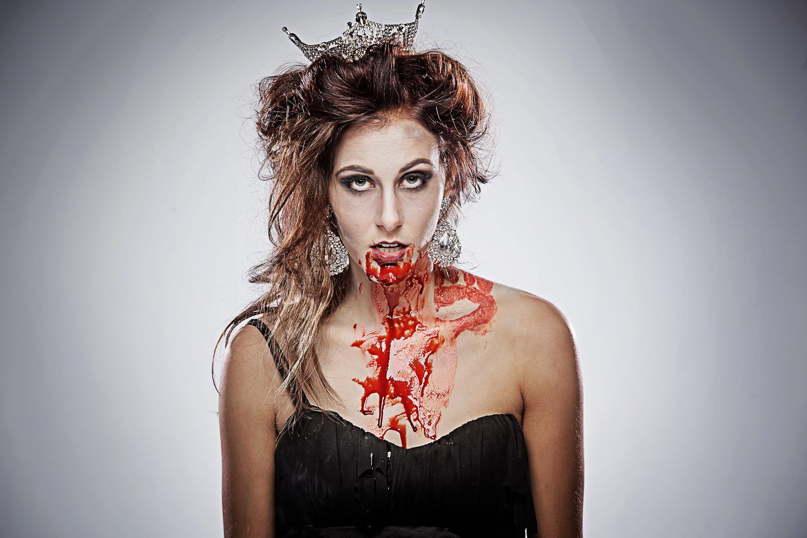 A contestant in zombie makeup wearing a crown, played for laughs